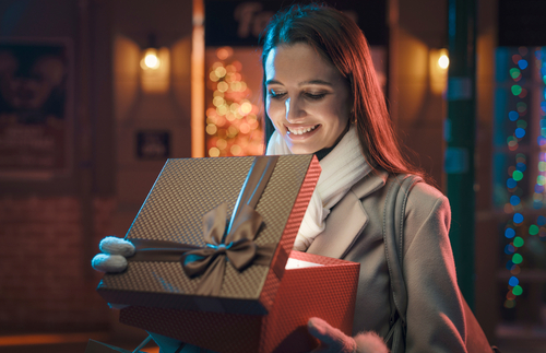 A smiling woman opening a glowing gift box